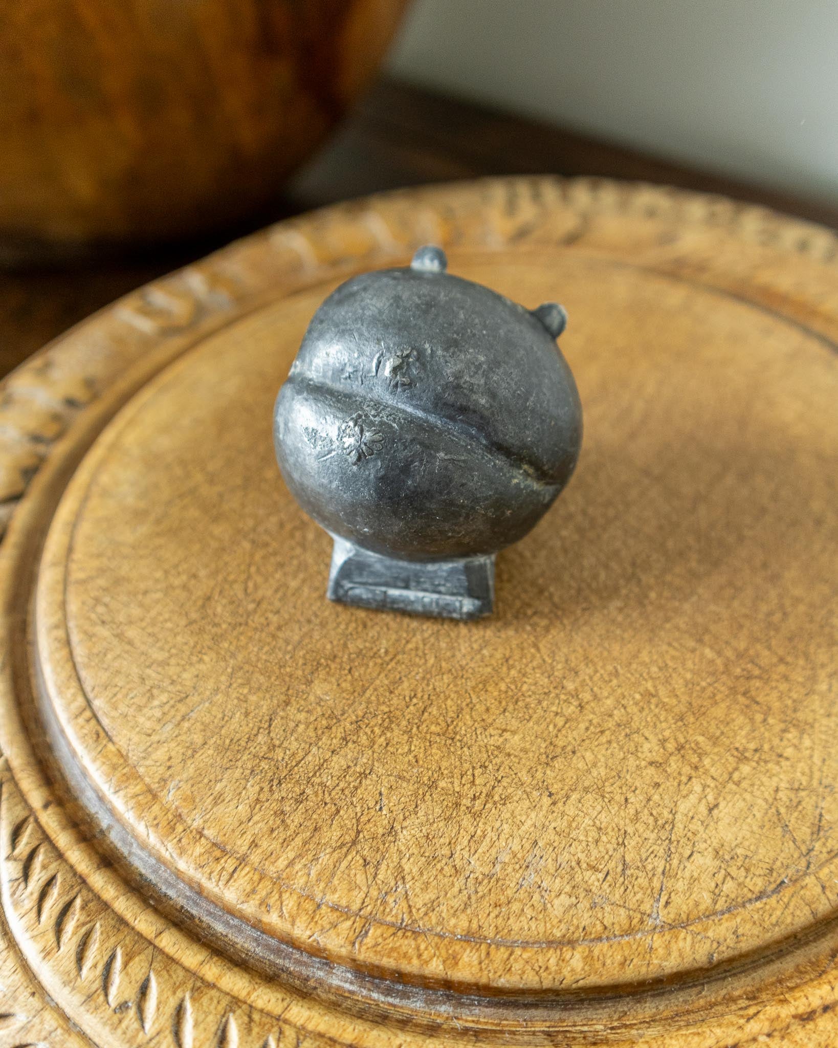Decorative wooden breadboard with a pewter mould on a dark background