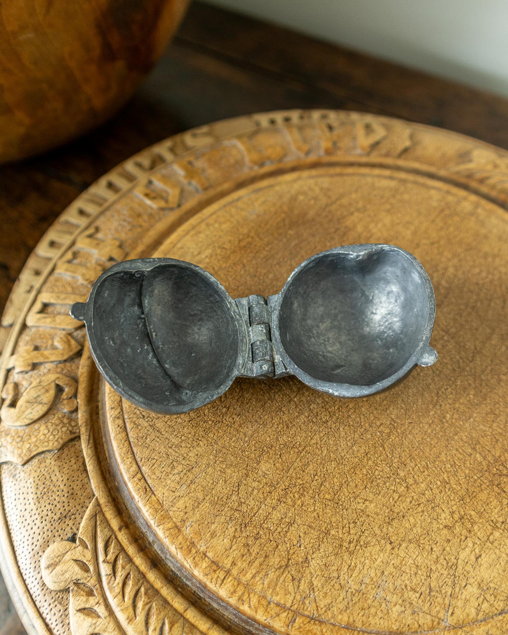 Decorative wooden breadboard with a pewter mould on a dark background