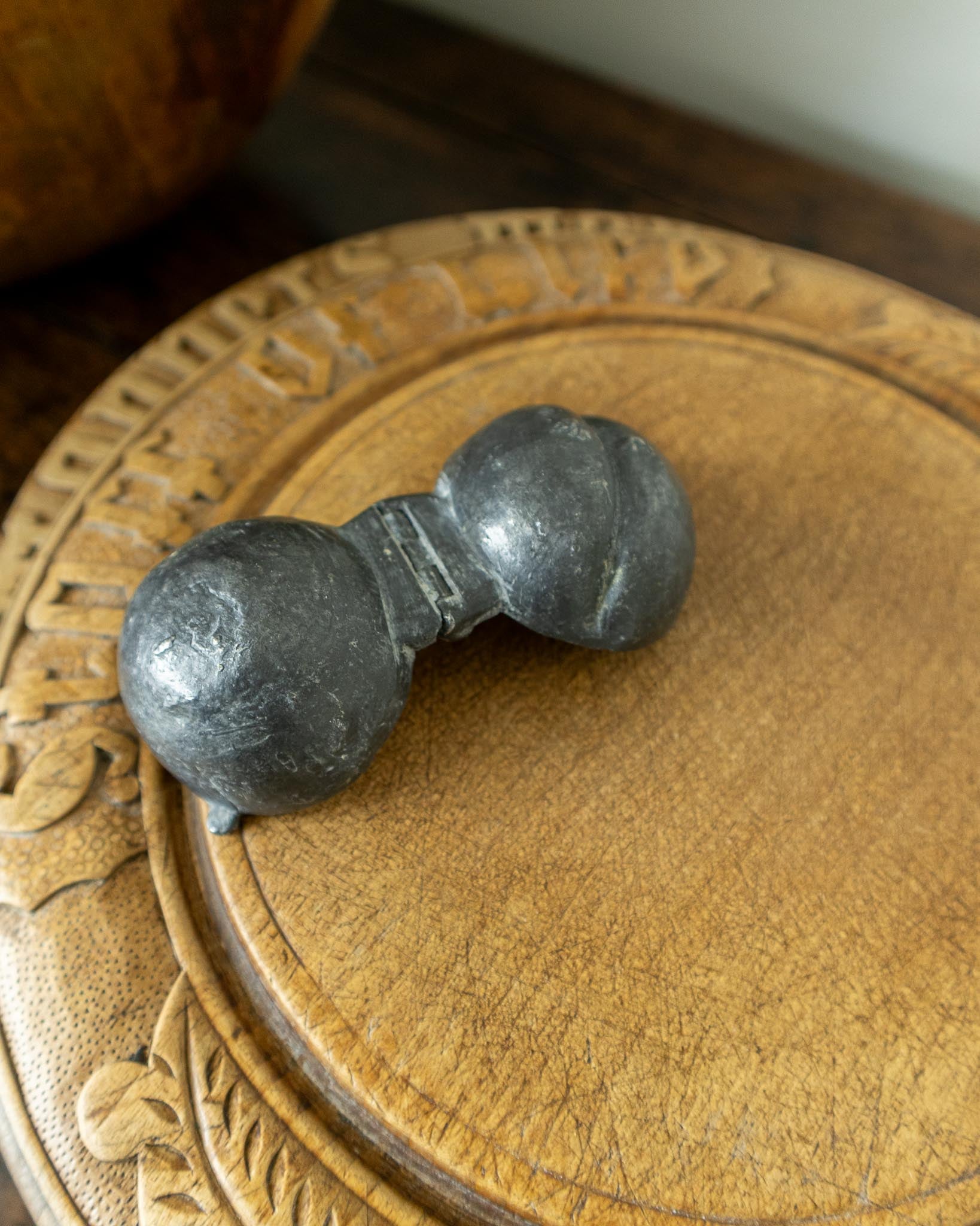 Decorative wooden breadboard with a pewter mould on a dark background
