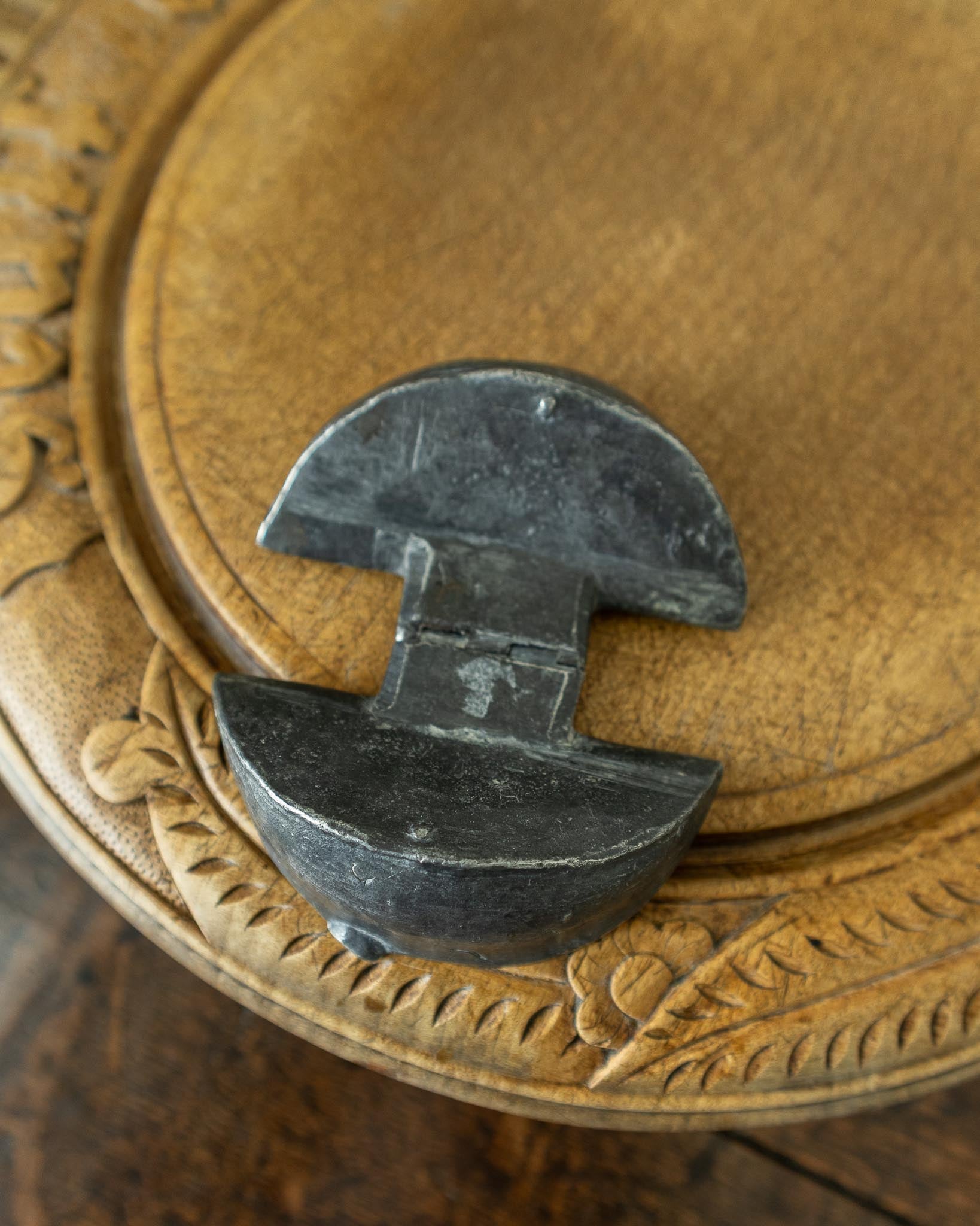 Decorative wooden breadboard with a pewter mould on a dark background