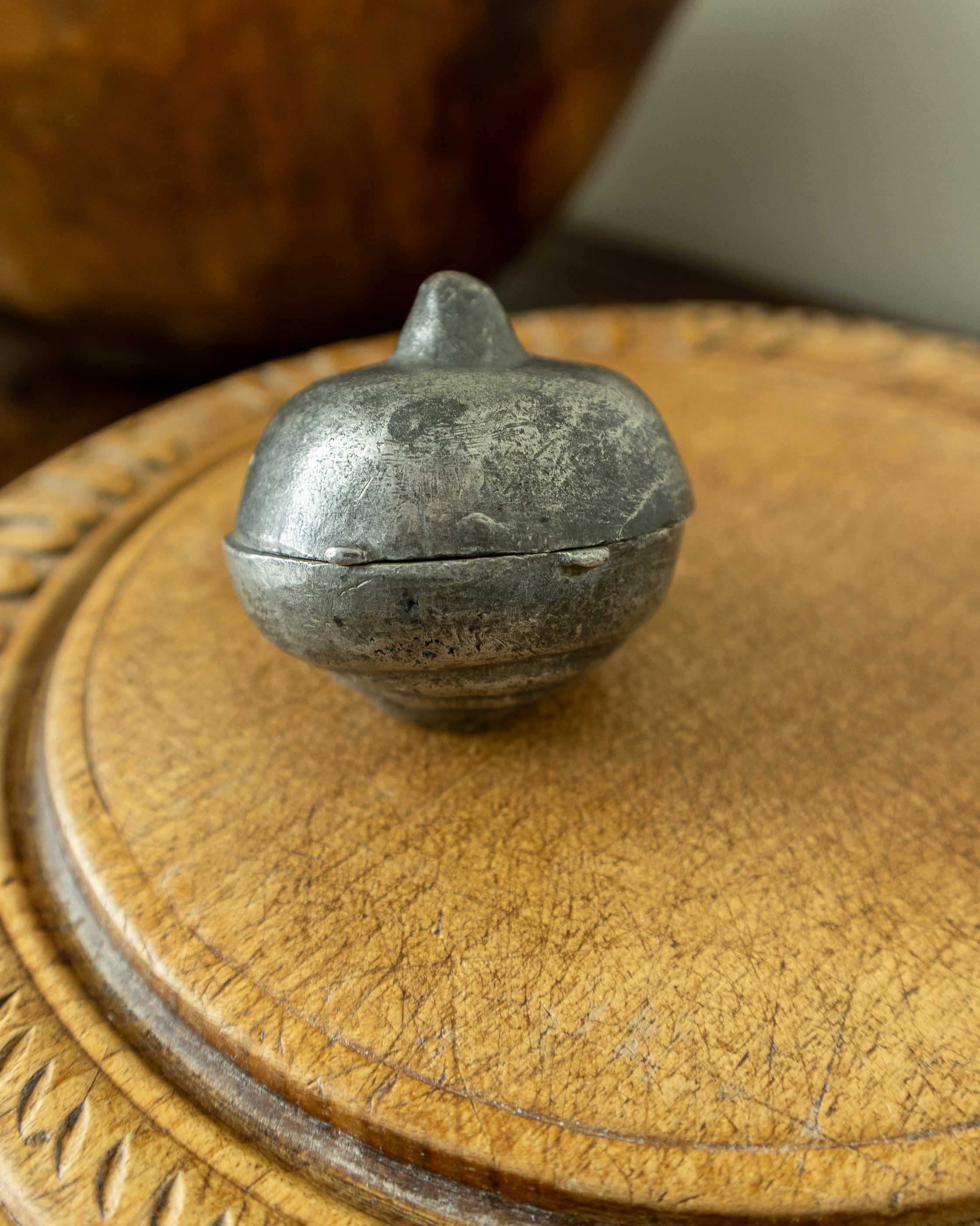 Decorative breadboard with a pewter mould on a wooden surface