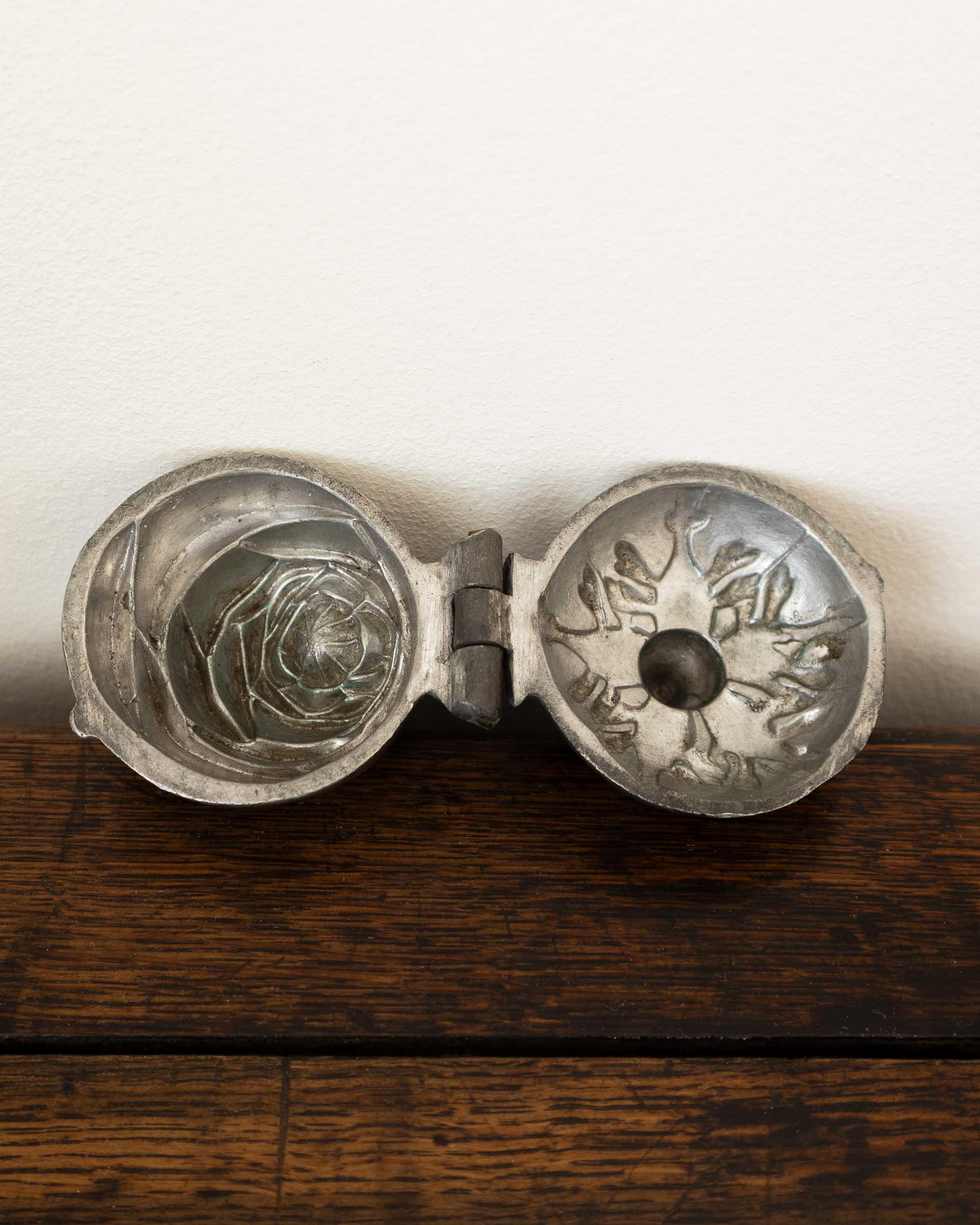 Pewter mould with intricate designs on a wooden surface