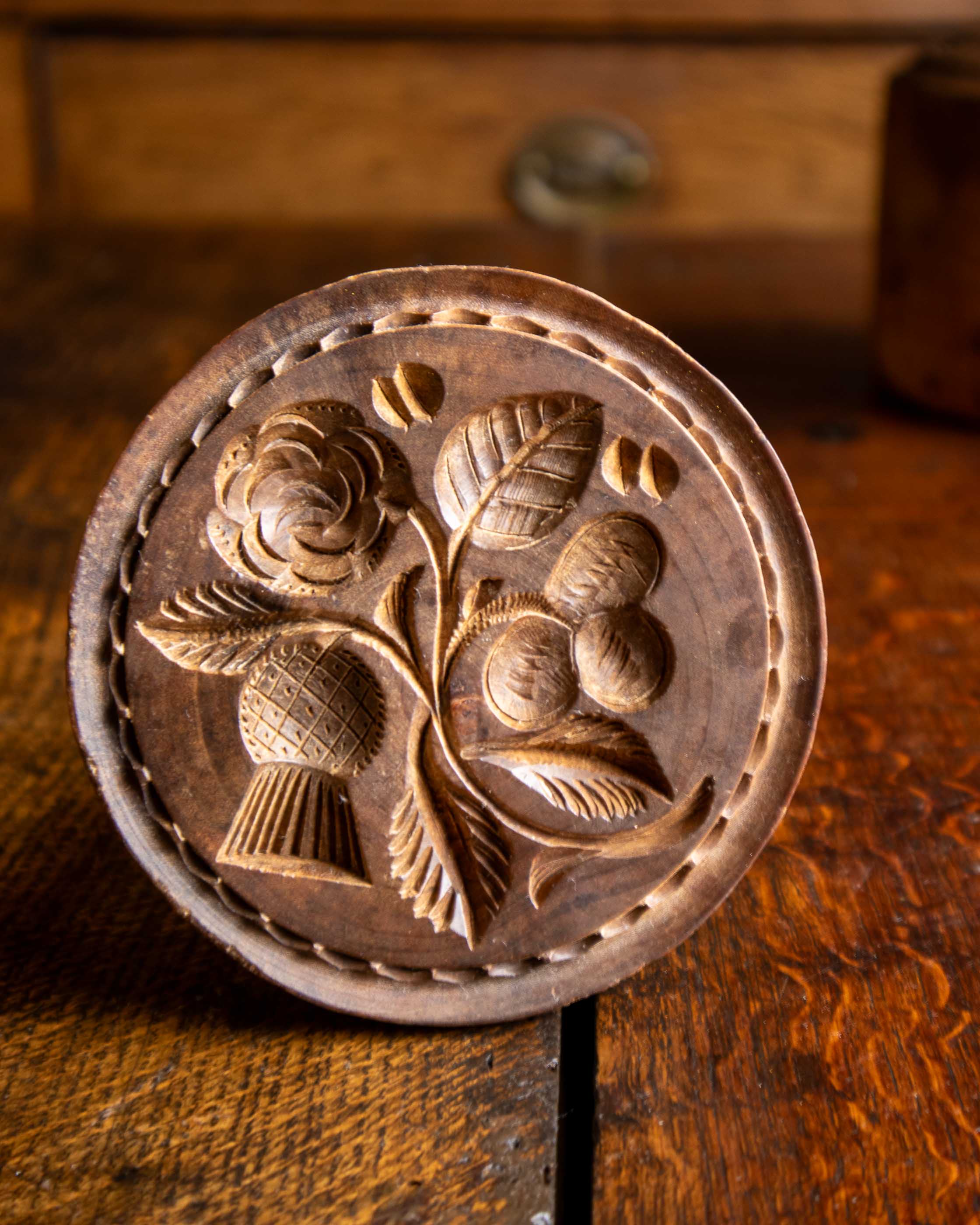 Wooden butter stamp with floral design on a wooden surface