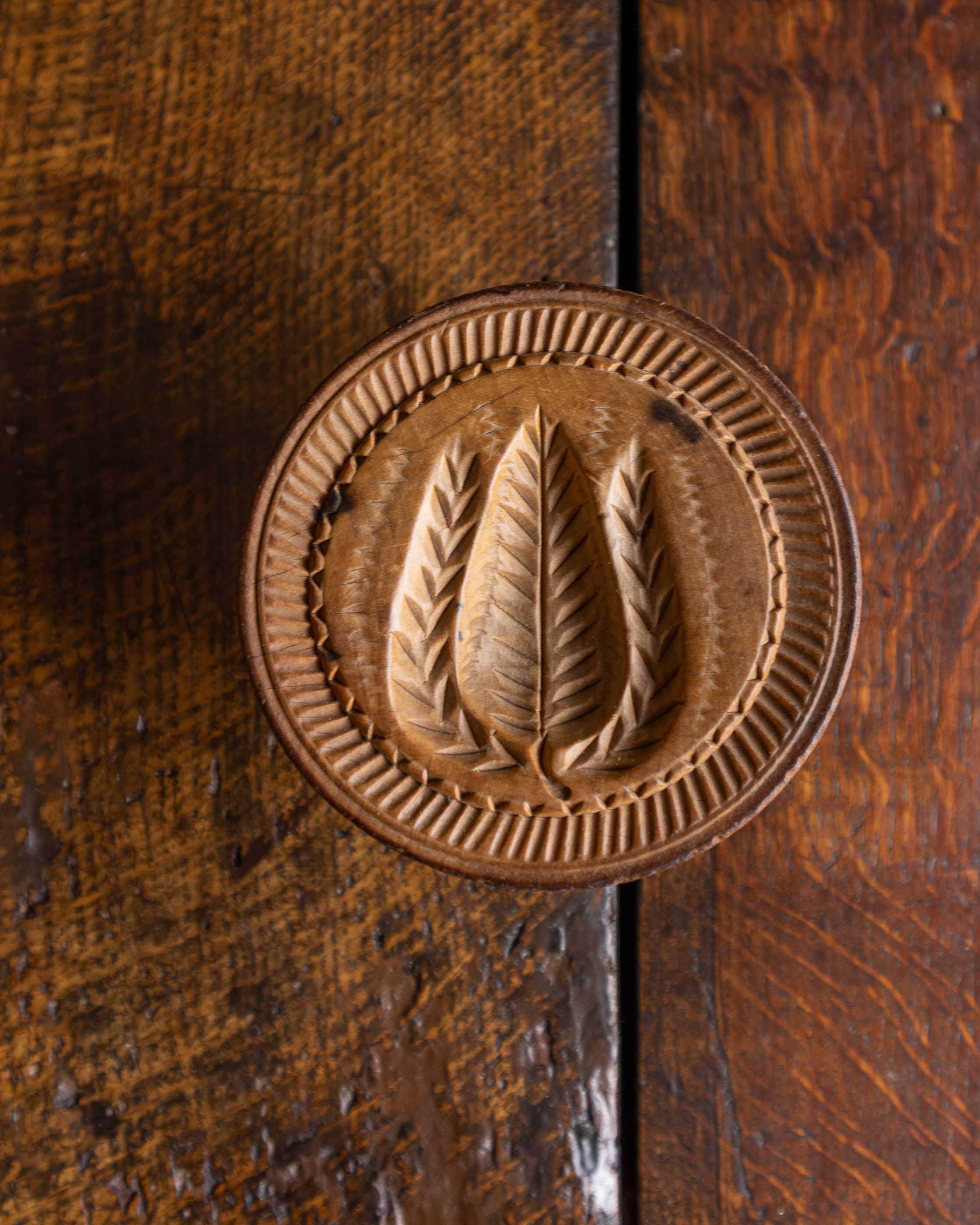 Wooden butter stamp with leaf design on a wooden surface