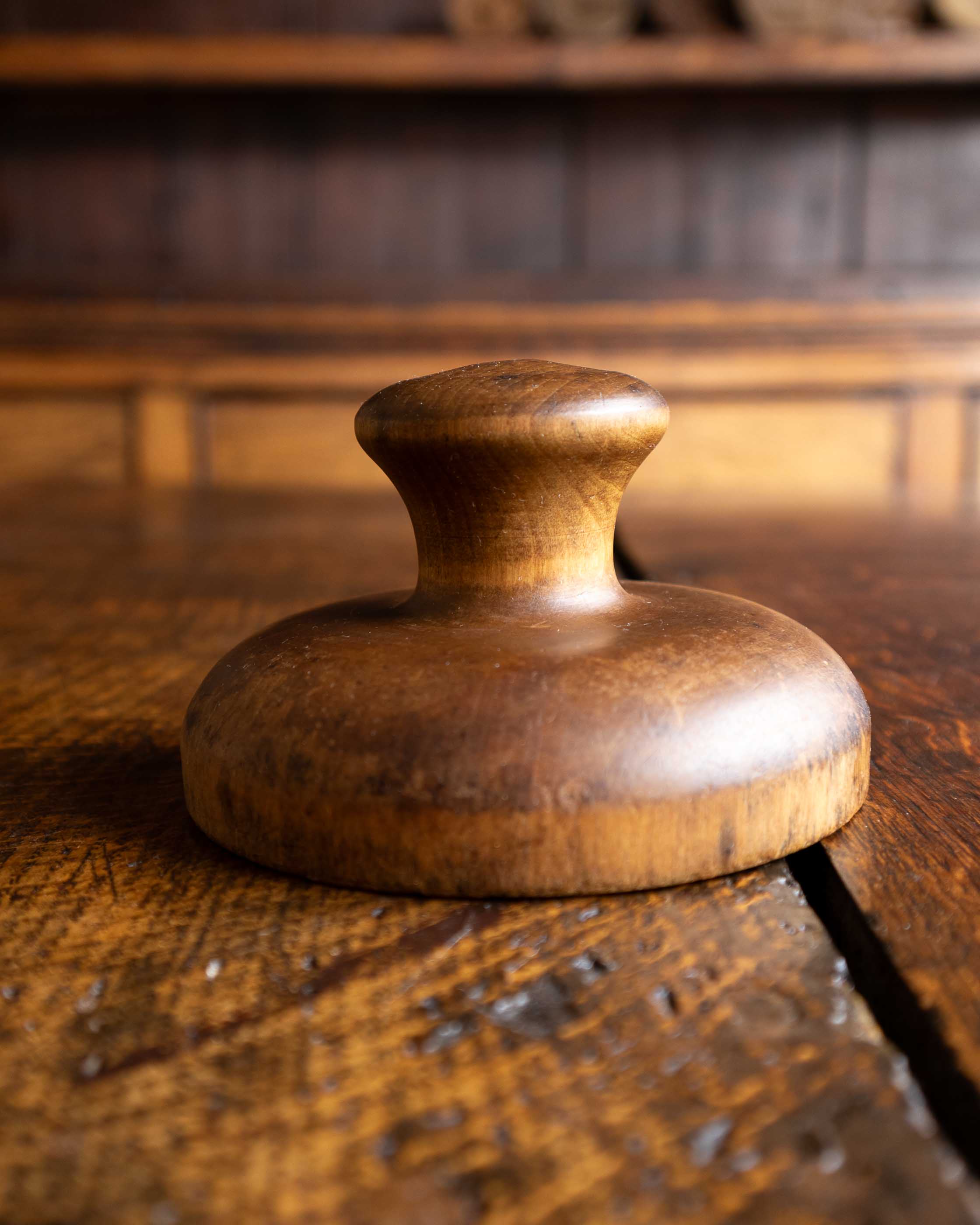 Wooden butter stamp handle on a wooden surface with a warm tone