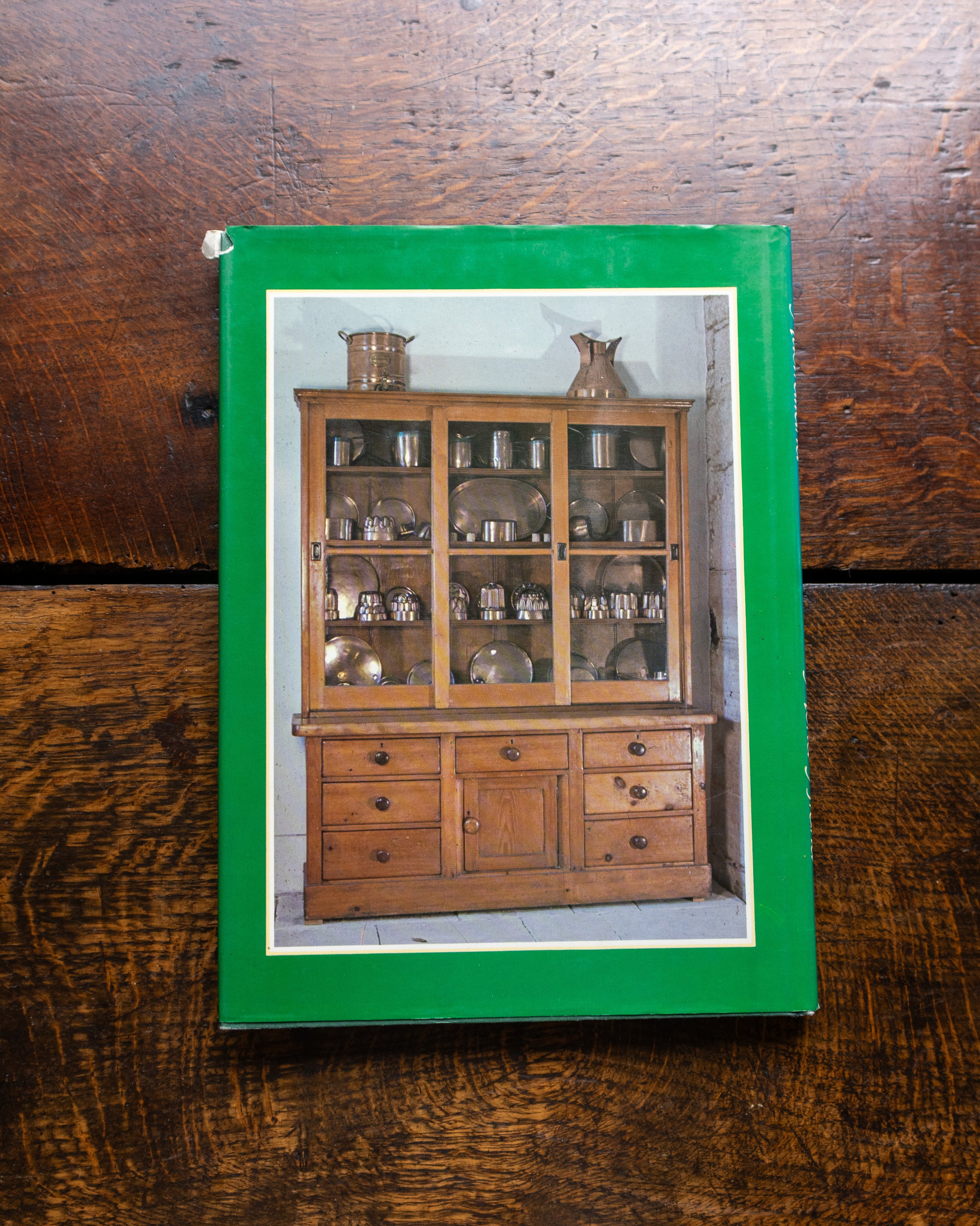Book cover with an image of a wooden cabinet on a wooden surface