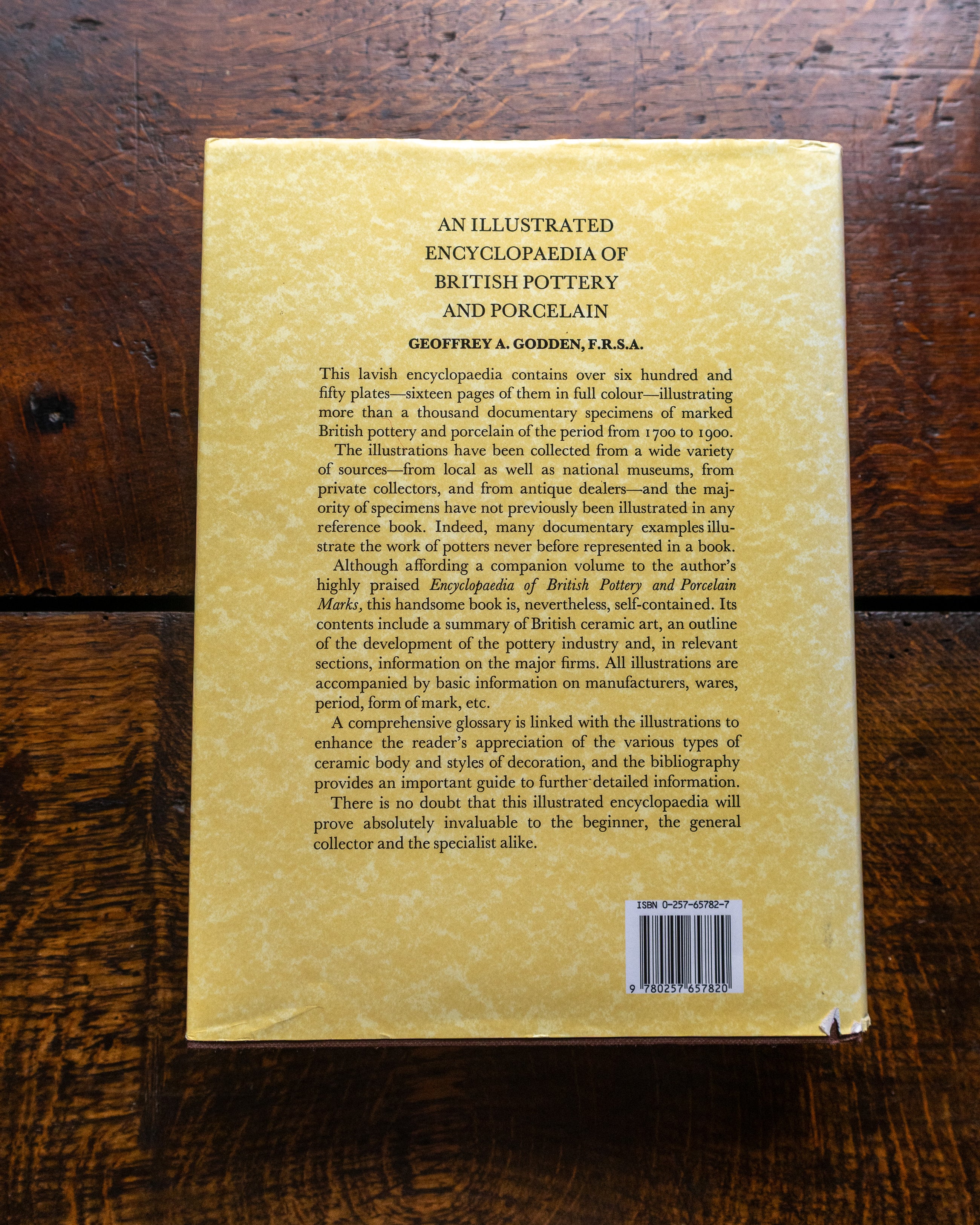 Back cover of an illustrated encyclopaedia of British pottery and porcelain on a wooden surface