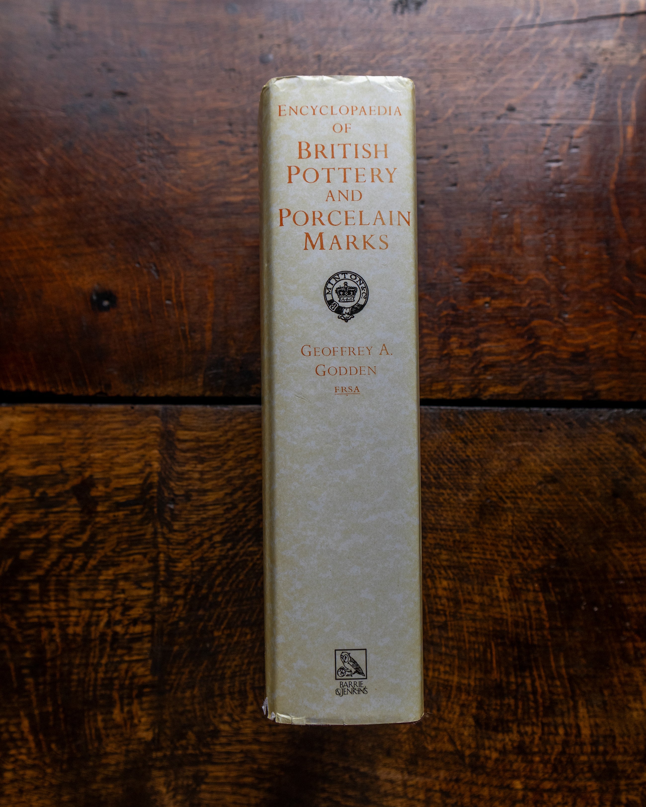 Book titled 'Encyclopedia of British Pottery and Porcelain Marks' on a wooden surface
