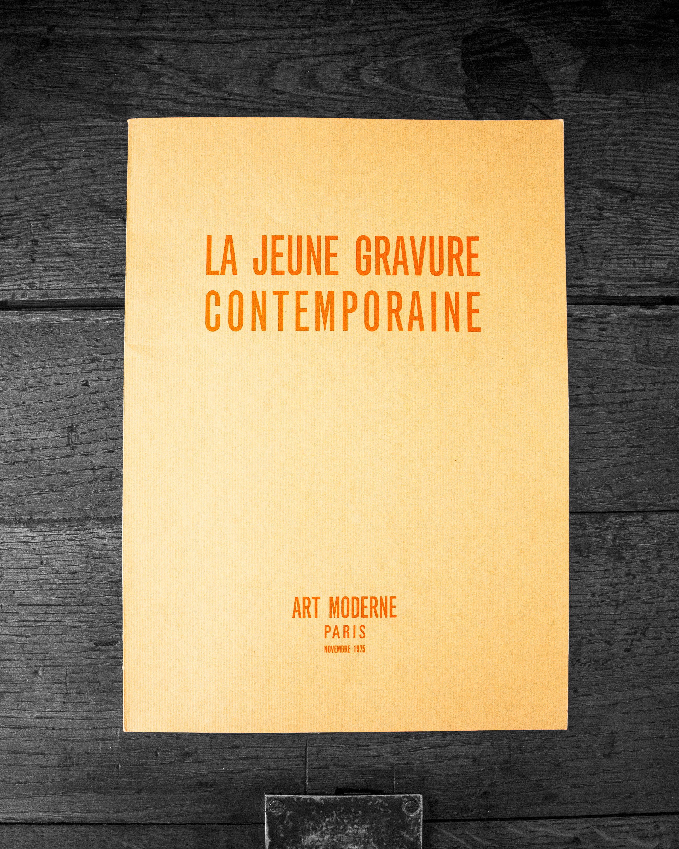Book cover with text 'LA JEUNE GRAVURE CONTEMPORAINE' on a dark wooden surface