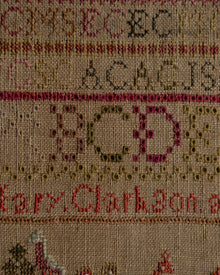 Sampler with embroidered letters and names on a beige background