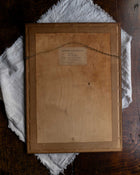 Back of a wooden frame with a label on a textured surface