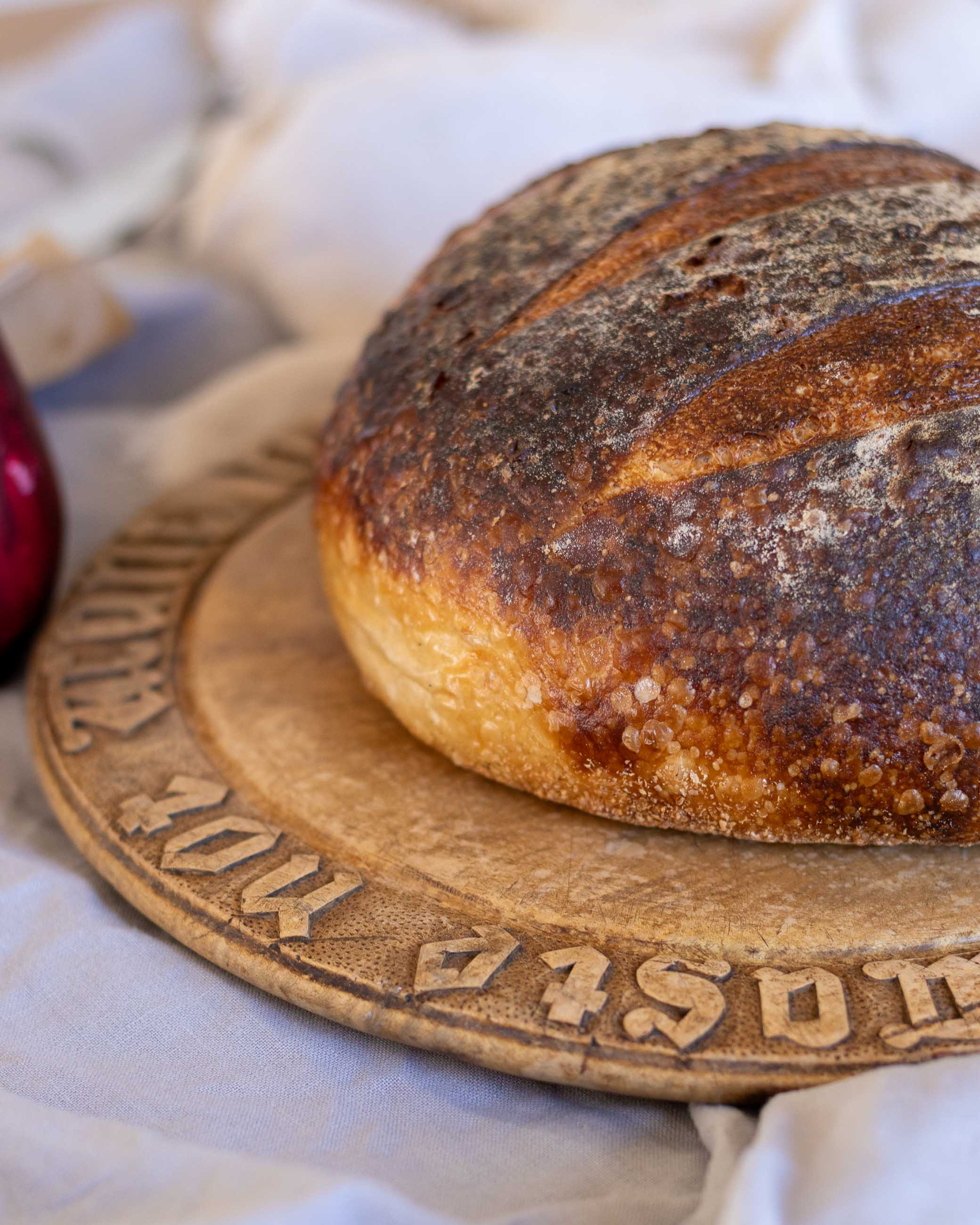 Loaf of bread on a decorative antique breadboard with a blurred background