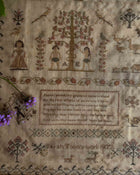 Antique embroidered sampler with text and decorative elements on a beige background
