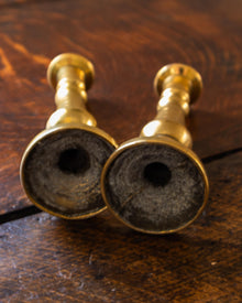 Two brass candlestick holders on a wooden surface