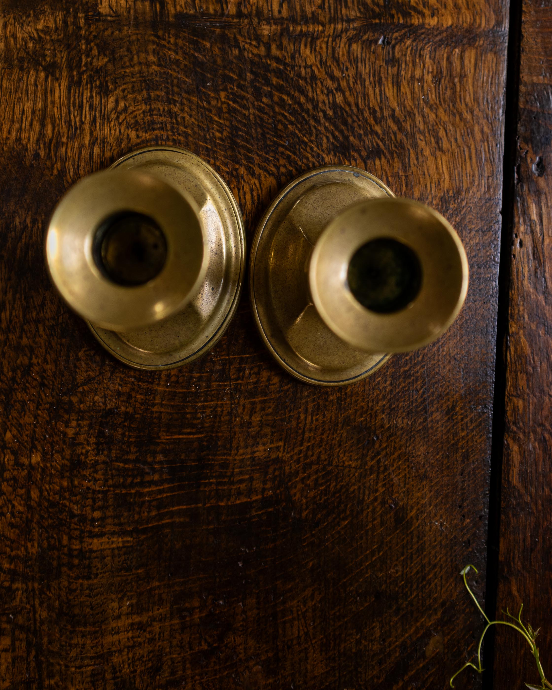 Two brass candle holders on a wooden surface