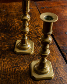 Two brass candlesticks on a wooden surface