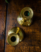 Two brass candle holders on a wooden surface