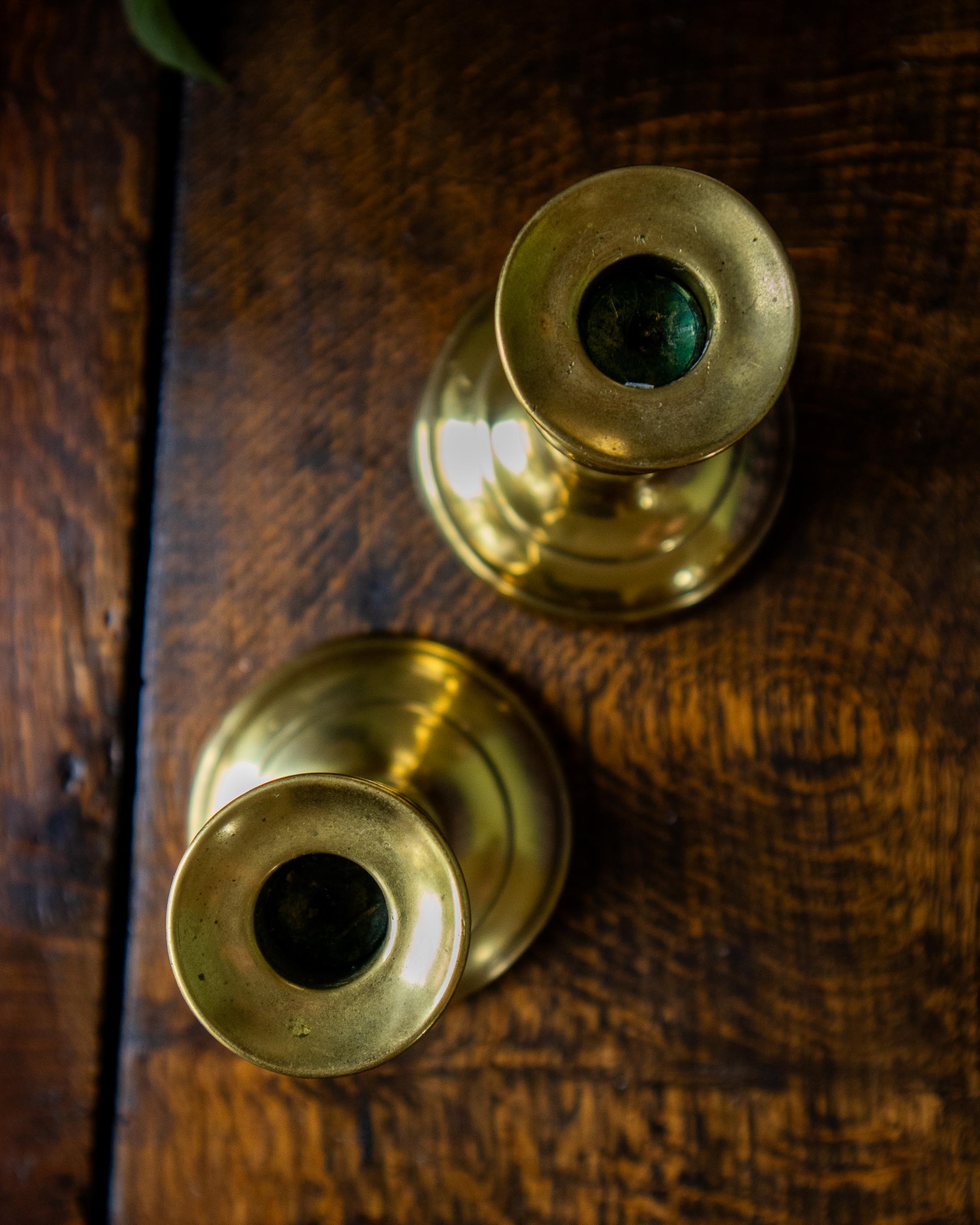 Two brass candle holders on a wooden surface