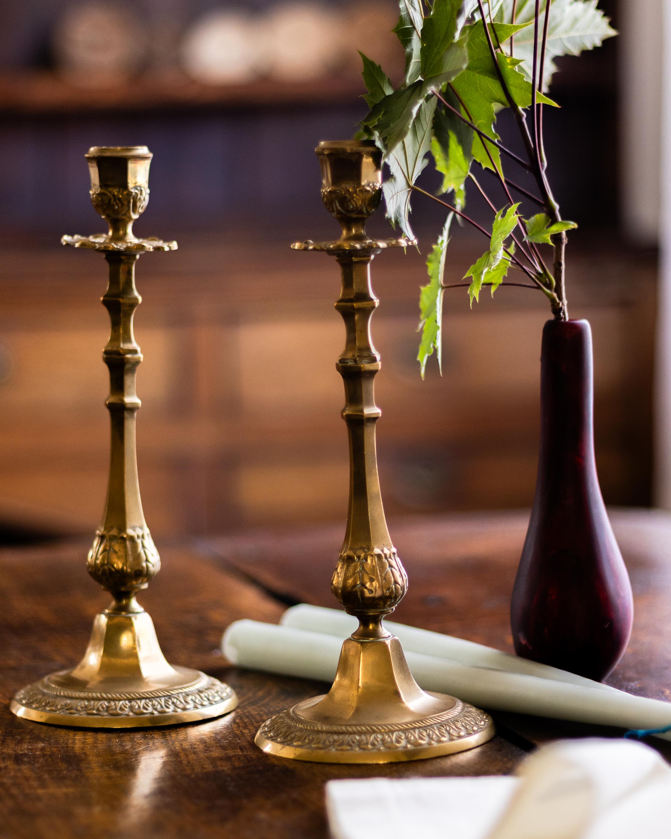 Two ornate brass candlesticks on a wooden surface with a blurred background
