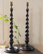 Two twisted wooden candlesticks on a wooden surface with a light background