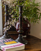 Decorative candlesticks with a vase and books on a wooden surface