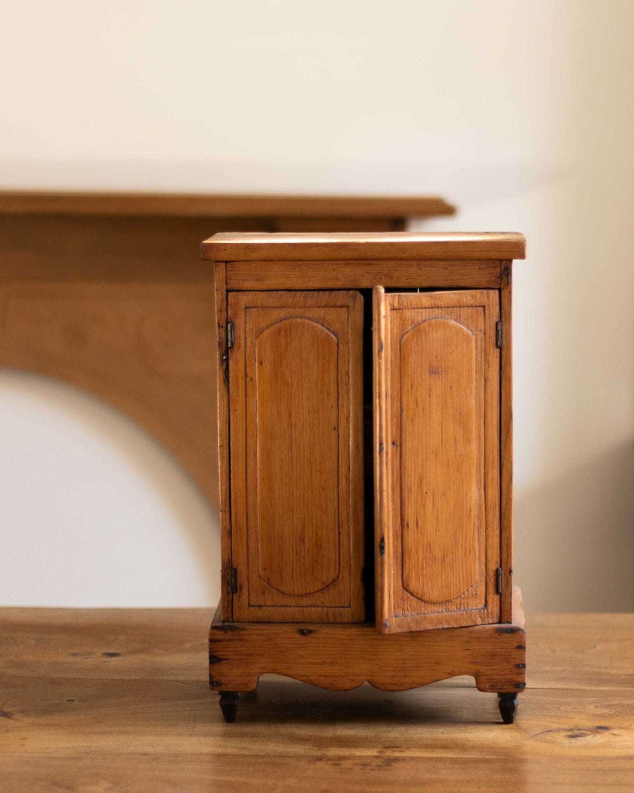 Small wooden cabinet with two doors on a wooden floor.