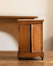 Small wooden cabinet with two doors on a wooden floor.