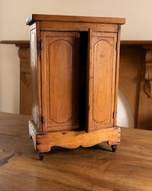 Small wooden cabinet with curved base on a wooden surface