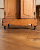 Close-up of a wooden cabinet with rounded corners on a wooden floor.