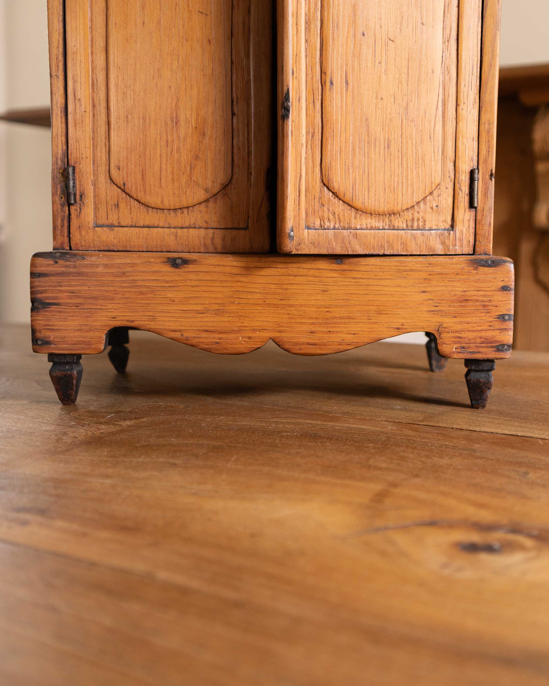 Close-up of a wooden cabinet with rounded corners on a wooden floor.