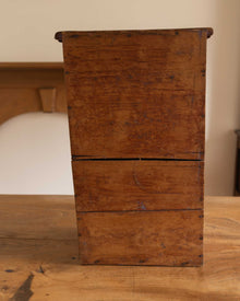 Wooden cabinet with two drawers on a wooden surface.