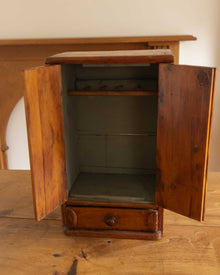 Wooden cabinet with open doors on a wooden surface