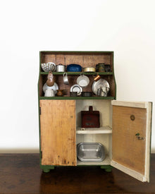 Wooden toy cabinet with open doors displaying various kitchen items on a white background