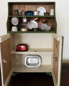 Wooden toy kitchen with shelves containing various toy kitchen items.