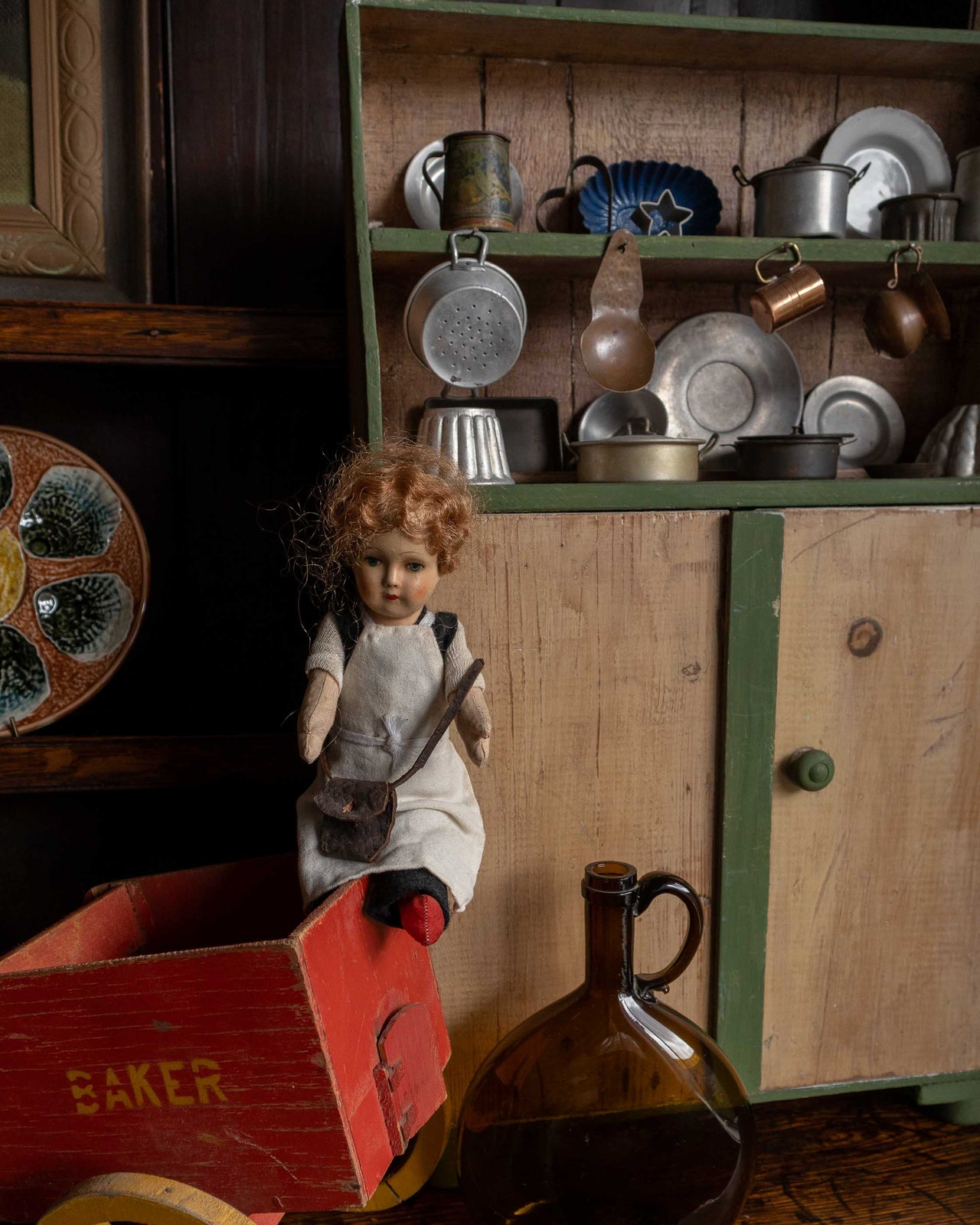 Vintage doll with a red cart and kitchenware in a rustic setting