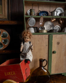 Vintage doll with a red cart and kitchenware in a rustic setting