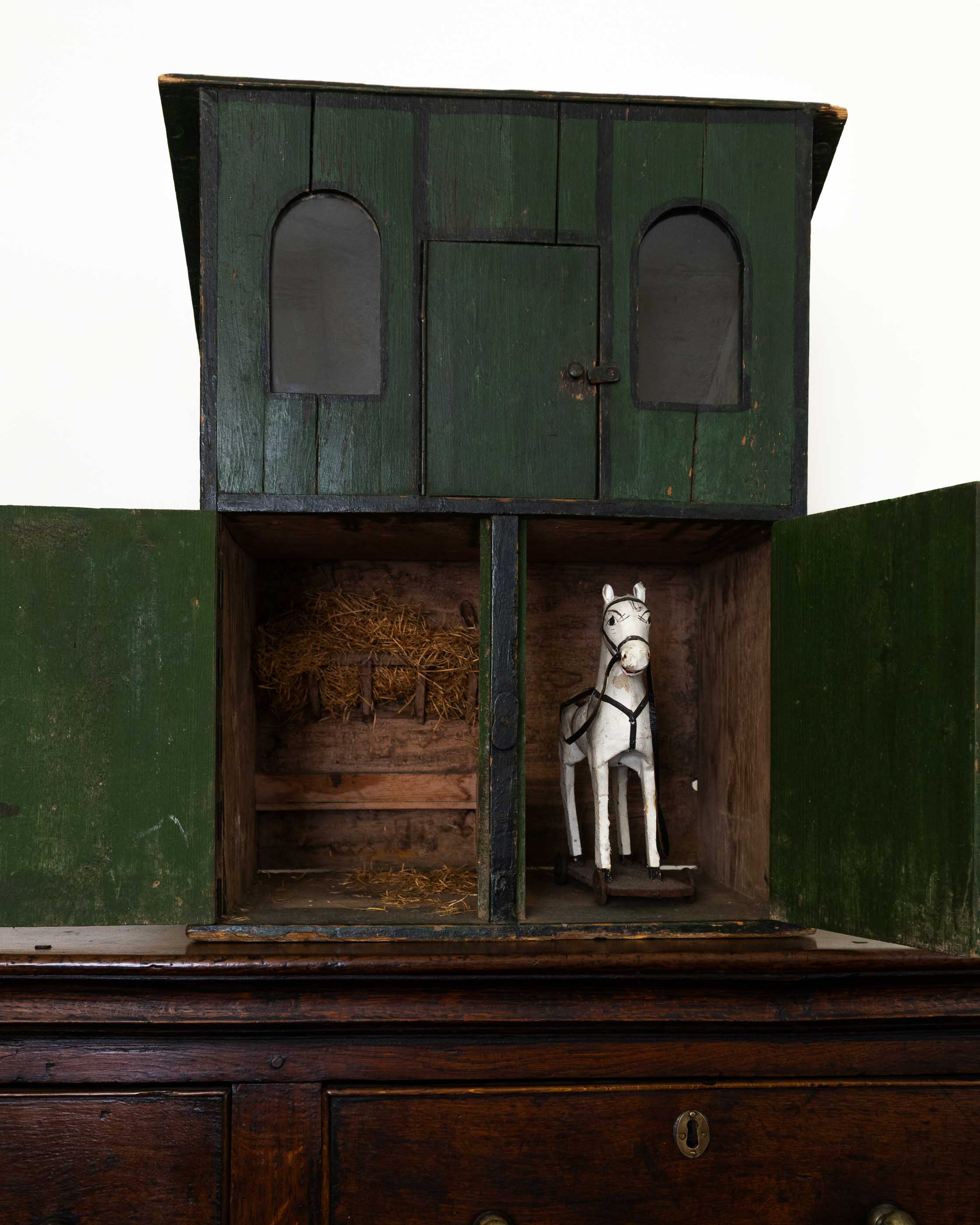Wooden horse stable with a toy horse inside on a white background