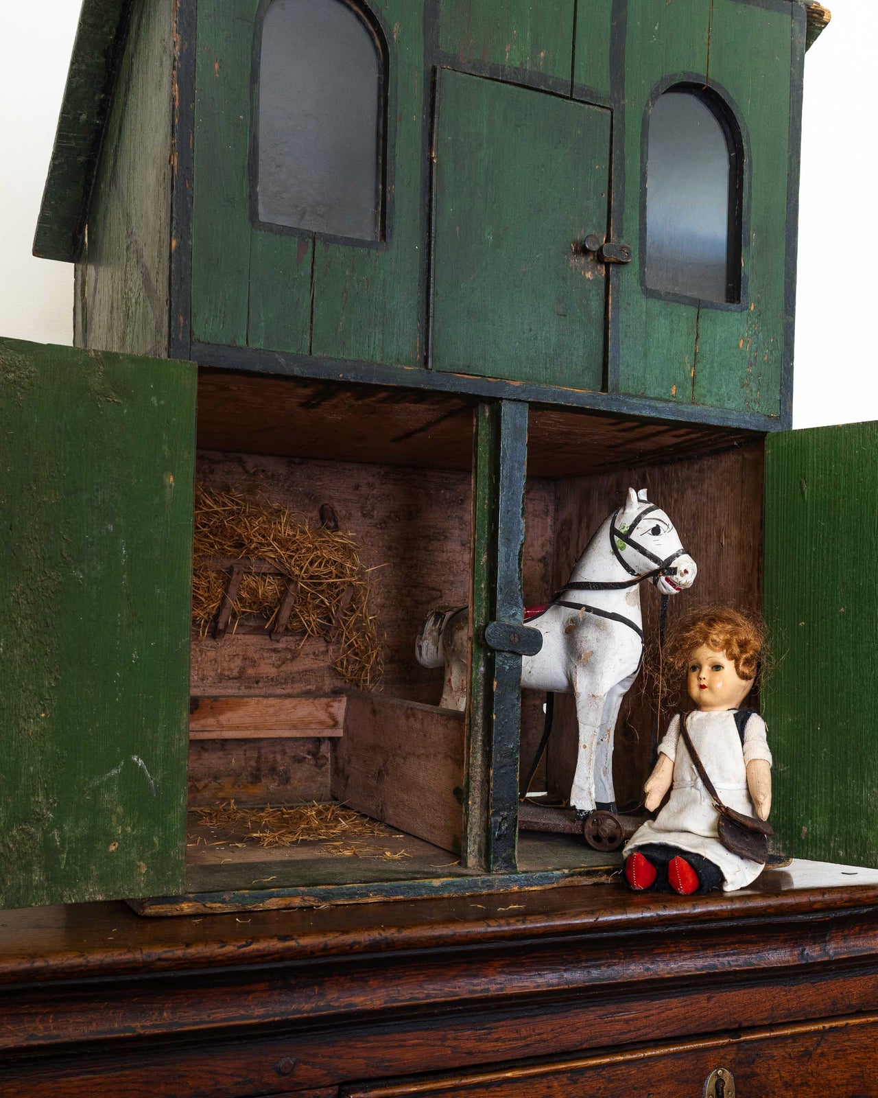 Small wooden stable with a horse and a doll on a white background