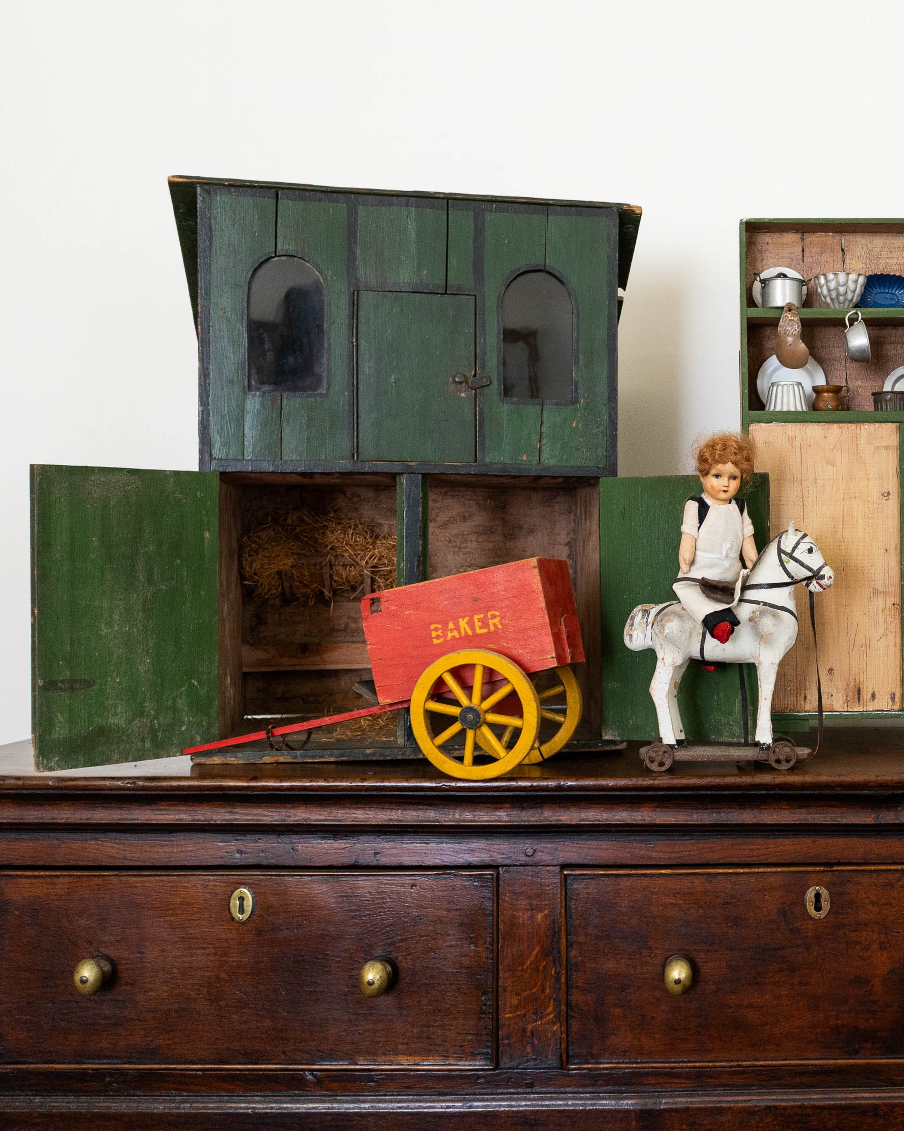 Vintage toy stable with a horse and cart on a wooden surface.