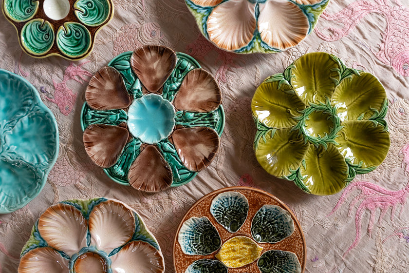 Collection of colorful majolica oyster plates with shells on a textured surface