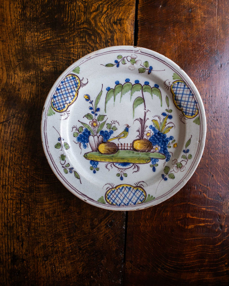Decorative ceramic plate with floral and landscape design on a wooden surface