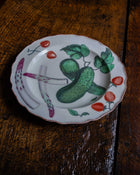 Decorative plate with a cucumber and strawberry design on a wooden surface