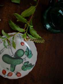 Decorative plate with green plant design on a wooden surface