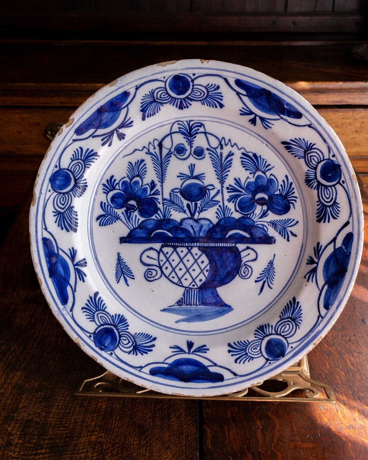 Blue and white decorative plate with floral and fruit design on a wooden surface