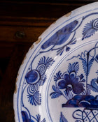 Close-up of a blue and white ceramic plate with floral patterns on a wooden surface.
