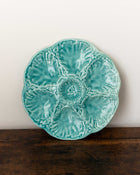 Turquoise ceramic plate with shell design on a wooden surface and white background