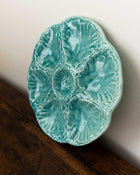 Turquoise ceramic plate with shell design on a wooden surface