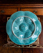 Turquoise ceramic plate on a decorative stand against a wooden background