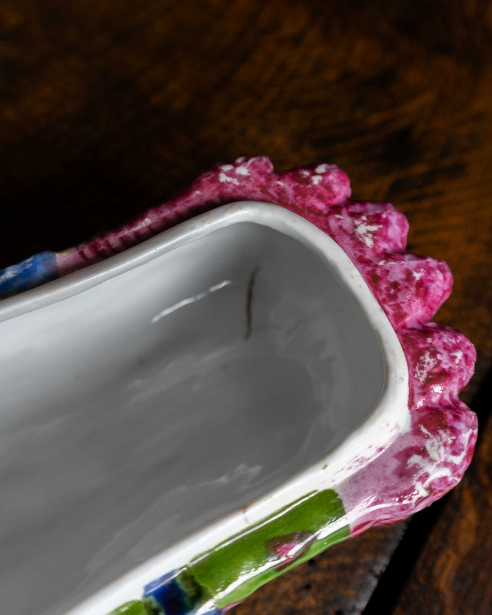Pink and green and blue ceramic asparagus box on a wooden surface