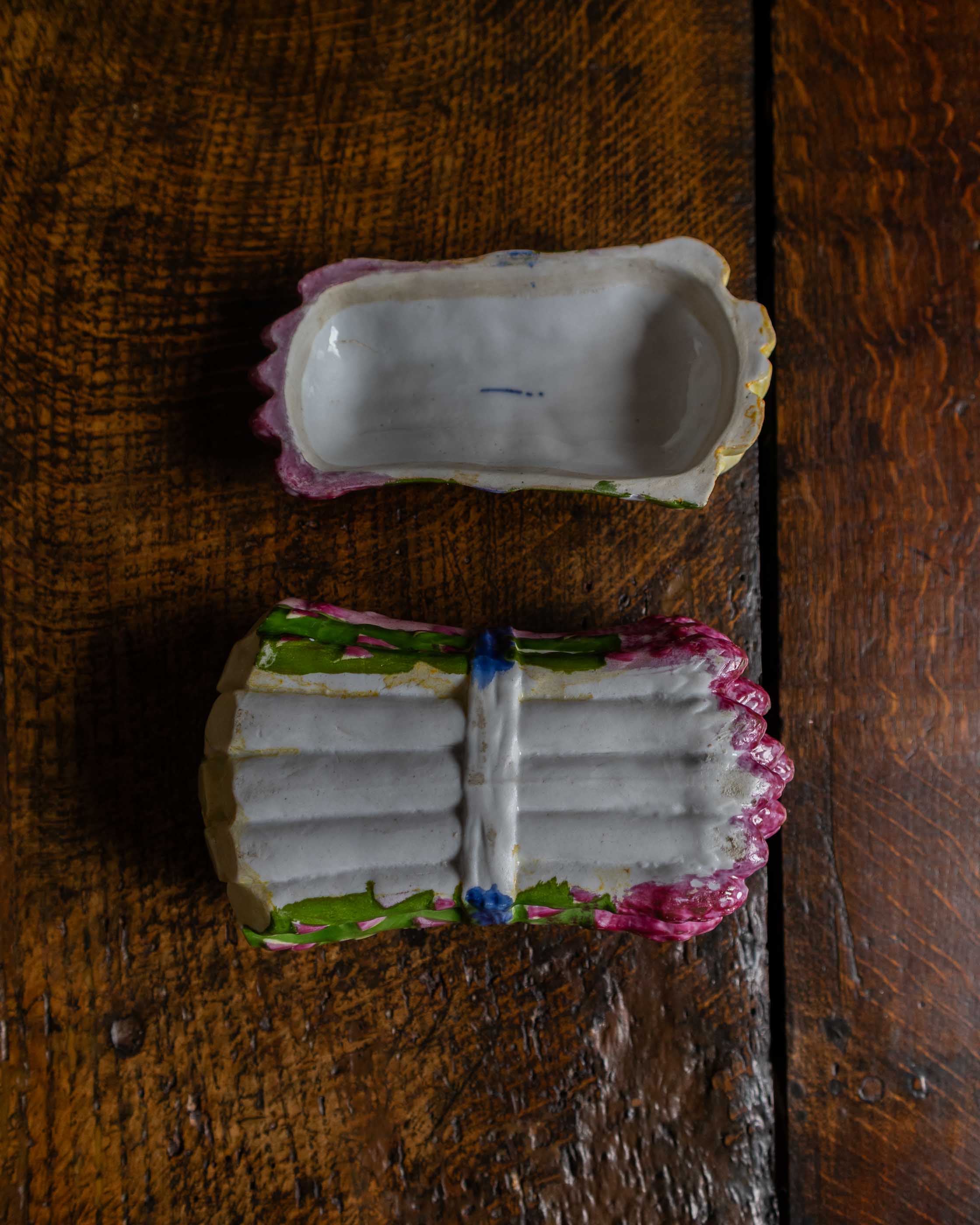 Pink and green and blue ceramic asparagus box on a wooden surface